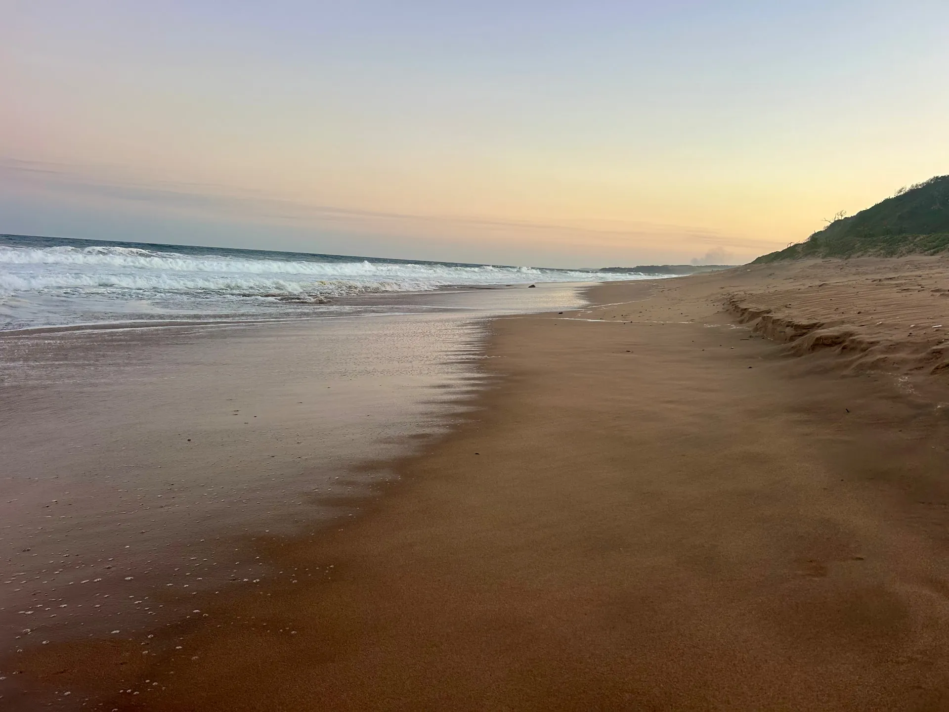 Empty beach at sunrise on the KZN north coast with waves washing over wet sand