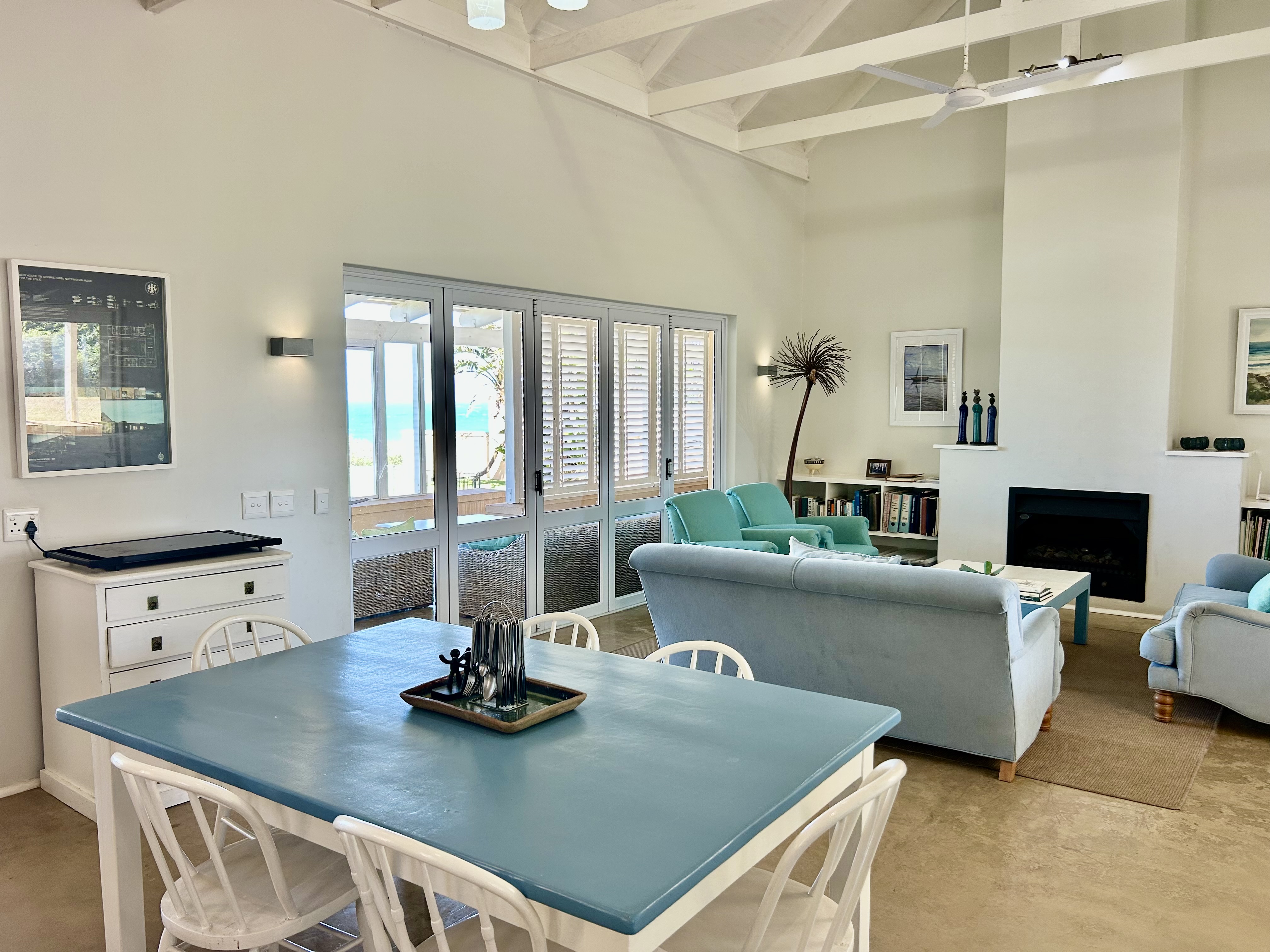 Warm family dining and living area at The Beach Cottage with ocean views through open windows